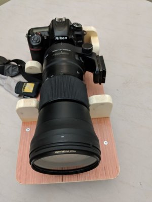 The curved cradle piece of wood is placed so that the rubber adjustment band of the lens rests on it.