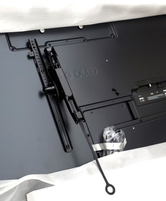 First bracket attached to the back of the TV, with hand-tightening screw on the outside edge that allows for holding the TV at a desired tilt.