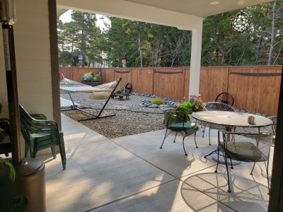 They have a covered patio on the back of the house with a golf course on the other side of the fence.