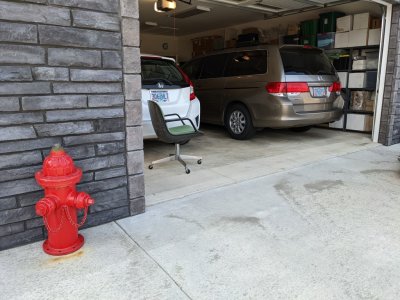 He keeps a chair in the garage where he sits to greet passersby.