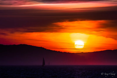 lone sail boat with setting sun