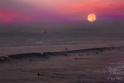 surfers and setting moon