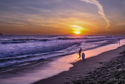 a surfer with its board at sunset