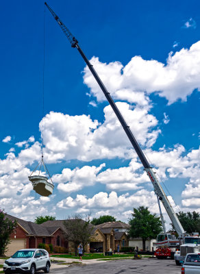 Large Crane lifting a pre-cast pool into the backyard of a residence. 