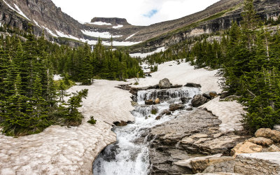 Mount Siysh and water running from beneath the snow at Siyeh Bend in Glacier National Park