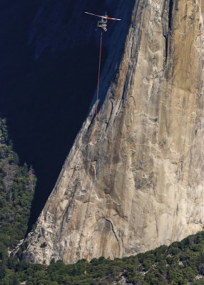 Helicopter transporting a team member as seen from Taft Point with the foot of El Capitan below in Yosemite National Park