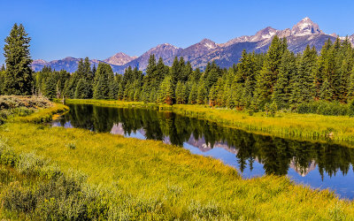 The Grand Teton Range reflected in a Snake River tributary at Schwabacher Landing in Grand Teton National Park