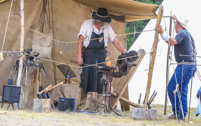 A blacksmith works in a tent at a fair outside of West Yellowstone Montana
