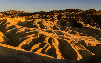 The late afternoon sun paints the hills around Zabriskie Point in Death Valley National Park