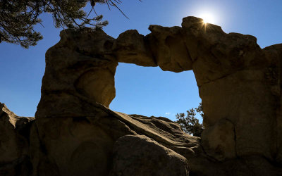 The sun peaks over Window Arch in City of Rocks National Reserve