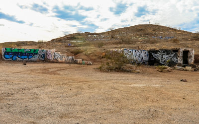 Buildings and a hillside covered in painted and rock graffiti along US Route 66