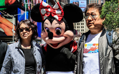 Mini Mouse poses for a picture with tourists in Times Square