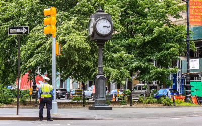 New York Police Department (NYPD) officer stands below a street clock tower in New York City
