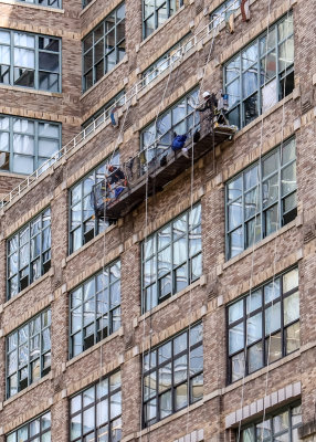 Window washers on a scaffold work high above New York City