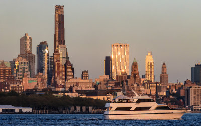 Yacht on the Hudson River sails by as sun reflects off of Brooklyn buildings 