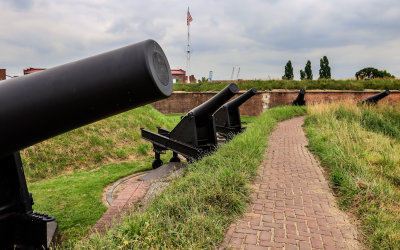Multiple guns with the fifteen-star flag in the background in Fort McHenry NM and HS