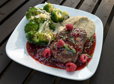 Venison patty over white bean puree with raspberry sauce, roasted broccoli