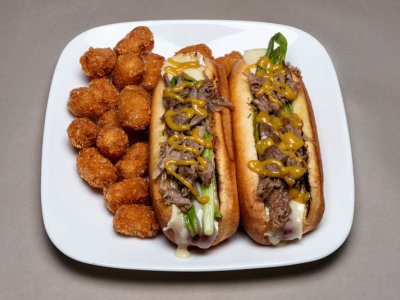 Hot dog on Brioche bun with Brie, Grilled Scallion, Duck Confit and Honey Mustard with Tater tots