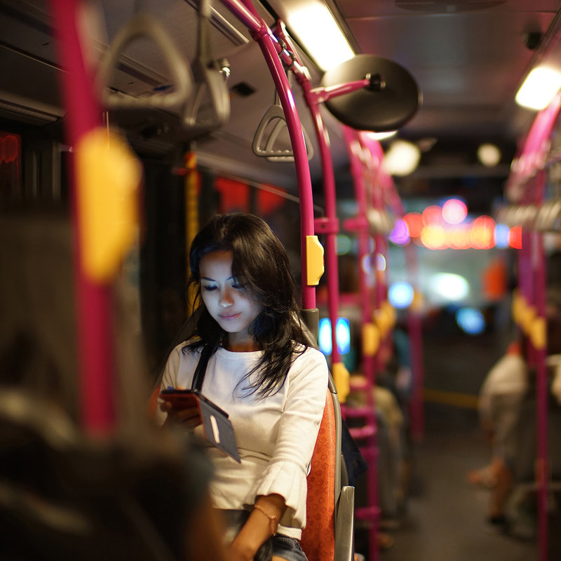 Bus passenger using smartphone, illuminating her face