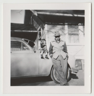 Unknown man and child sitting on car