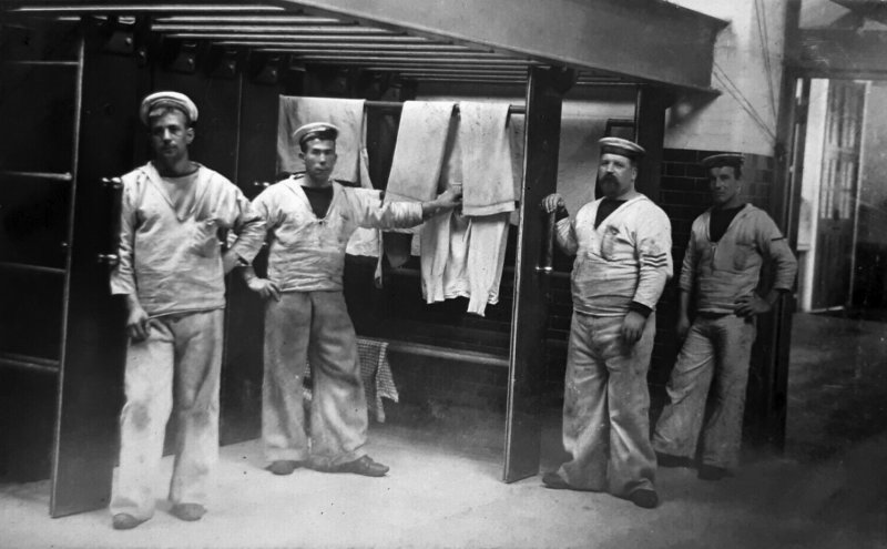 1914c - 4 POSSIBLE INSTRUCTORS BESIDE THE DRYERS IN THE LAUNDRY.jpg