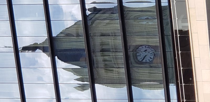 Reflection of clock tower in nearby skyscraper.