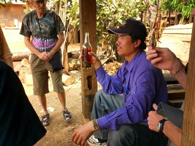 Our guide and driver explaning how to drink Lao Lao, Lao rice whiskey - near Phonsavon