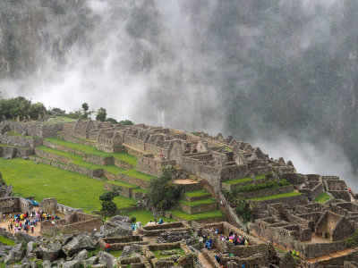 Mist rises in the valley behind the central plaza in Machu Picchu