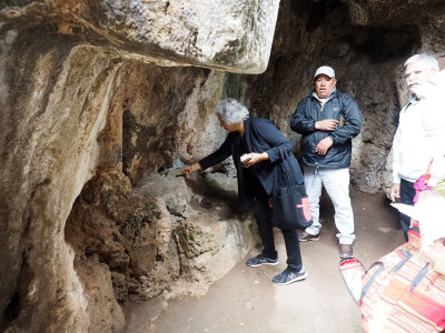 Making an offering to Pachamamma in a rock tunnel at Sacsayhuaman