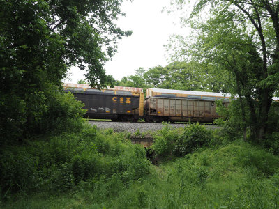 CSX freight train rolling past parked autocars