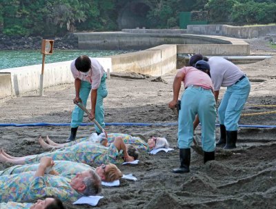 Volcanic sand is shoveled over participants