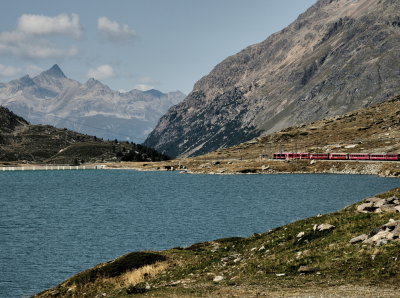 Red train along the blue lake