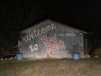 Welcome to Red Rock sign lit by truck headlights. 