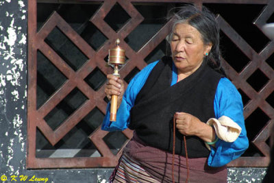 An old lady was rotating a prayer wheel