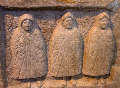 Three carved cloaked figures