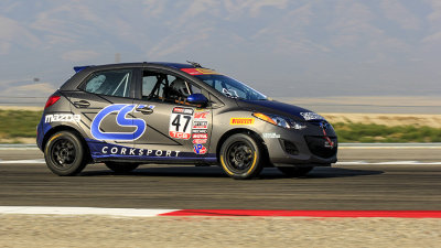 A Mazda 4 door economy car racing.