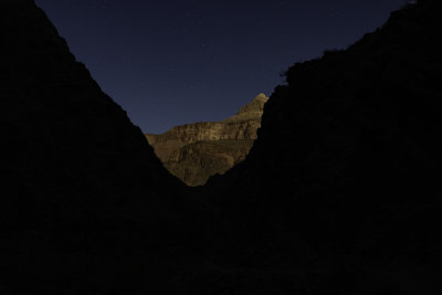 The walls on the north side of the Colorado River - illuminated by moonlight - appear through the gap ahead