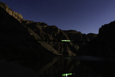 A hiker with a bright greenish headlamp crosses Kaibab Bridge in this 15 second exposure