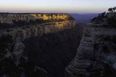 Along the rim, the first light of sunrise hits the upper layers of the Canyon