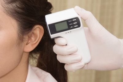 Doctor's hand checking woman's ear with infra-red digital thermometer