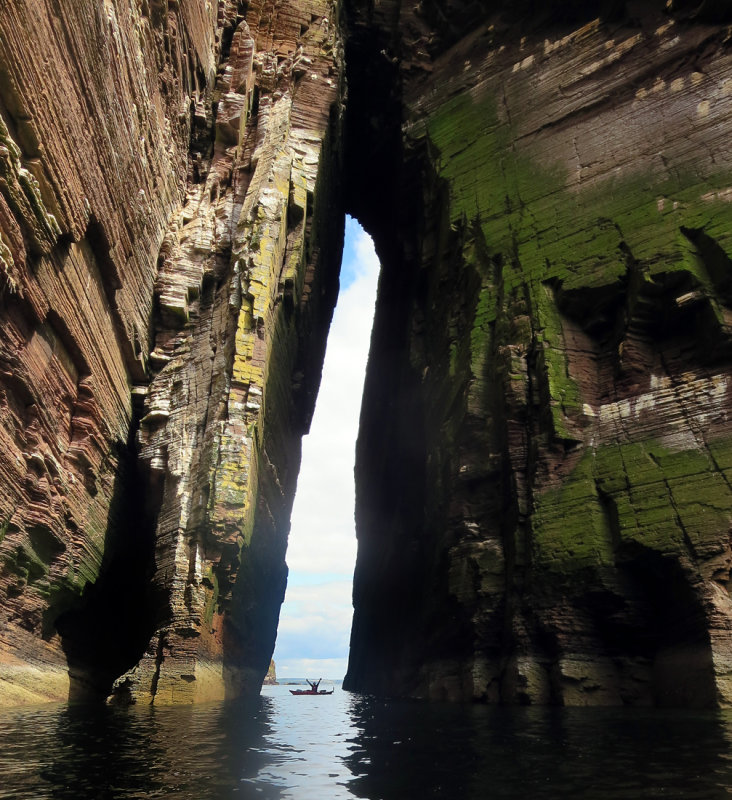 Sea kayaking under An Dun arch north of Berriedale, NE Scotland