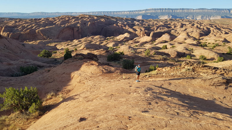 Heading east on slickrock slabs with 50 mile cliffs behind