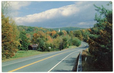 The white steeple of a country church stands out brilliantly against the colorful foliage of early fall