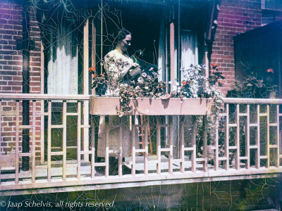 Autochrome portrait of lady watering plants on balcony