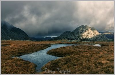 A dark and moody scene at Llyn Caseg Fraith with Tryfan in the background.