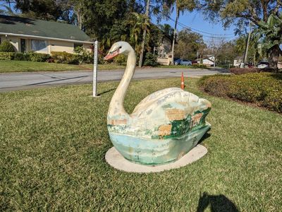 Another swan figurine in a yard across from the lake