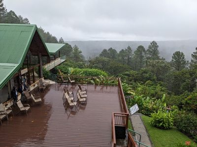 Another wet day at the Arenal Observatory Lodge; the dining room is on the left, Lake Arenal is in the background. The deck overlooks some of their gardens and bird feeders.