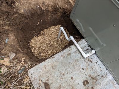 The condensation drain for the old unit simply ran out onto the ground, but this time they dug a ditch, filled it with gravel and ran the drain into it.