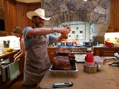 Angela checks the oven while Seth does something to a big chunk of pork.