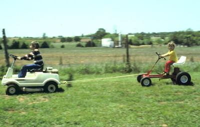 Jeremy driving his grandfather Davis' lawnmower and pulling Seth on a lawnmower frame, in Mustang, OK